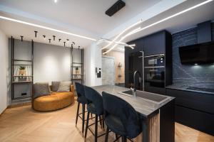 a kitchen with black cabinets and a bar with stools at #Dahlia by halu! Apartments in Thessaloniki