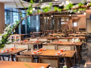 um restaurante vazio com mesas e cadeiras de madeira em Gao Shi Di Hot Spring Hotel Yangzhou em Yangzhou