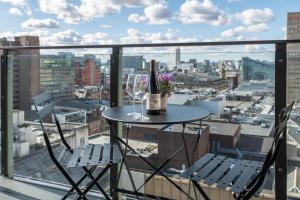 einen Tisch mit zwei Gläsern und Weinflaschen auf dem Balkon in der Unterkunft Church Street by Supercity Aparthotels in Manchester