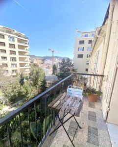 un banc en bois assis sur un balcon avec des bâtiments dans l'établissement Esperanto, à Cannes