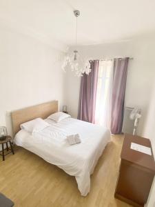 ein Schlafzimmer mit einem weißen Bett und einem Kronleuchter in der Unterkunft Esperanto in Cannes