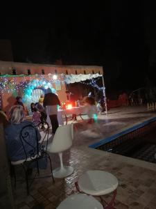 un groupe de personnes assises autour d'une piscine la nuit dans l'établissement Tiworgua, à Marrakech