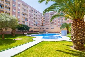 un edificio de apartamentos con una piscina y una palmera en Espanatour SAN JULIAN 41, en Torrevieja