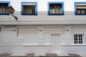 un edificio blanco con ventanas azules y una puerta en Hostal Alicia, en Marbella