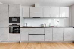 a white kitchen with stainless steel appliances and wood floors at Charming 1 BR apt , town centre, wifi, free parking by Tent Serviced Apartments in Staines