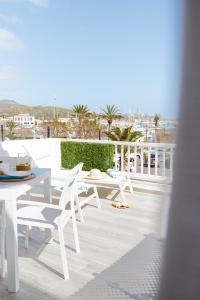 a patio with white tables and chairs on a balcony at Veronica Beachfront Apartment by FESEAL in Port de Pollensa