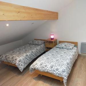 Habitación con 2 camas y mesa con lámpara. en Appartement rez de jardin en Saint-Martin-dʼUriage