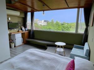 a bedroom with a bed and a desk and a window at 田中歐寒集b&b in Dongshan