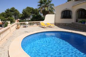 a swimming pool with two chairs next to a house at Superb villa with heated private pool - stunning sea and mountain views- Air con in Teulada