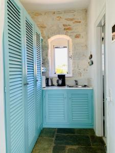 een blauwe badkamer met een wastafel en een raam bij Santa Maria Traditional Stone Studio in Santa Marina