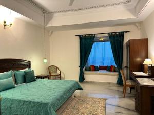a bedroom with a green bed and a window at Sardargarh Heritage Fort Udaipur in Sardārgarh +49 photos