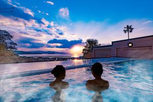 佐世保的住宿－TAOYA Saikaibashi，两人坐在游泳池里,欣赏日落