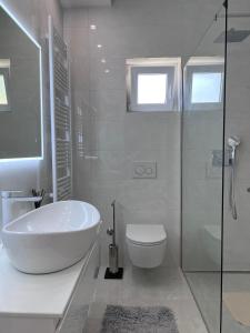a white bathroom with a sink and a toilet at Two Palms in Duće