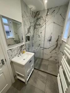 ein weißes Bad mit einem Waschbecken und einer Dusche in der Unterkunft Beach Lodge in Bournemouth