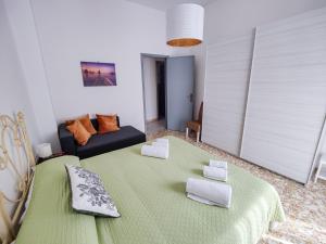 uma sala de estar com uma cama verde e um sofá em Fermata Cappuccini em Acireale