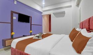 FabHotel Elite Residency في إندوري: غرفة نوم مع سرير كبير وتلفزيون على الحائط