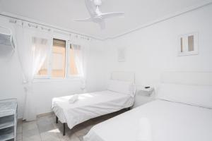 two beds in a white room with a window at Hostal Alicia in Marbella