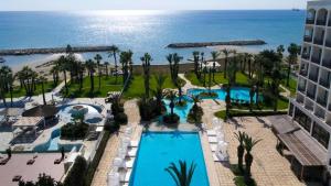 an aerial view of a resort with a pool and the ocean at Sandy Beach Hotel & Spa - ex Sentido in Larnaca