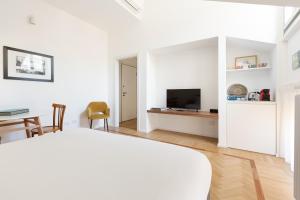Habitación blanca con cama, mesa y TV. en Spiga 46 Suites by Brera Apartments, en Milán