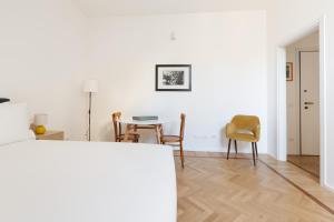 una sala de estar blanca con mesa y sillas en Spiga 46 Suites by Brera Apartments, en Milán