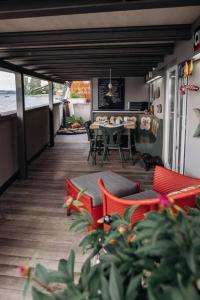 un patio avec des chaises rouges et une table sur une terrasse dans l'établissement Seehüüsli Suite / Lake House Suite, à Berlingen