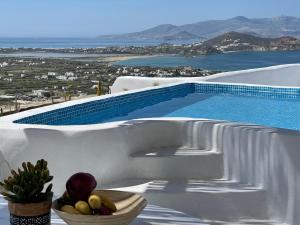 a bowl of fruit on a table next to a swimming pool at Eye of Naxos in Naxos Chora