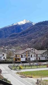 una calle con casas y una montaña cubierta de nieve en La Casa Di Sabi, en Locana