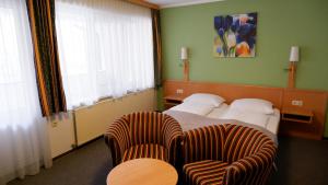 ein Hotelzimmer mit einem Bett und zwei Stühlen in der Unterkunft Gasthof Pils in Eschenau