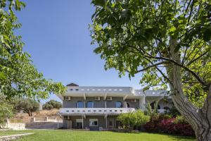 uma grande casa branca com uma árvore em primeiro plano em Green View Studios & Apartments em Dhamnóni