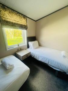 two beds in a small room with a window at Evergreen Lodge with Hot Tub in York