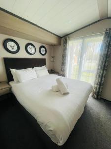 a large white bed in a bedroom with clocks on the wall at Evergreen Lodge with Hot Tub in York