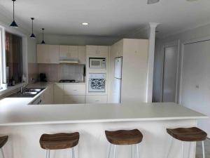 a kitchen with a white counter top and wooden stools at 4 bedroom family holiday home with large deck in Blairgowrie