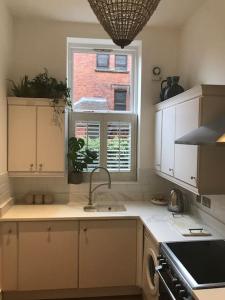 una cucina con armadi bianchi, lavandino e finestra di Lakeside View Arts and Craft Apartment a Liverpool