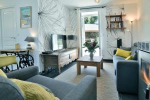 a living room with a couch and a tv at Ty Karet - Maison pour 6 proche plage in Saint-Cast-le-Guildo