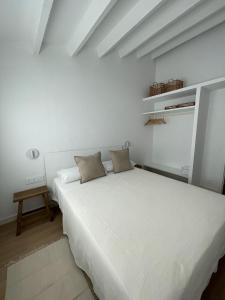 a white bedroom with a large bed and a table at Habitatges Turístics Riba Pitxot - Norai in Cadaqués