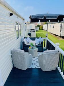 a patio with wicker chairs and a table and an umbrella at Crandley Manor Lodge in Whitstable