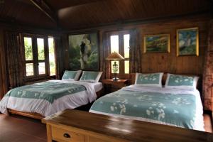 2 camas en una habitación con paredes y ventanas de madera en Zen Cafe Countryside Retreat 