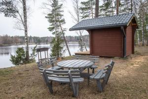 a picnic table and chairs in front of a cabin at Alberta Dīķi in Upesciems