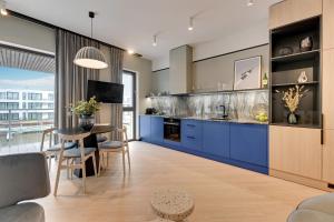 een keuken met blauwe kasten en een tafel met stoelen bij Downtown Apartments Riverview Sol Marina Sobieszewo - Pool, SPA, Wellness & Parking in Wiślinka