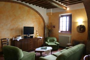 a living room with a couch and chairs and a tv at Villa Il Poggiarone in Montepulciano