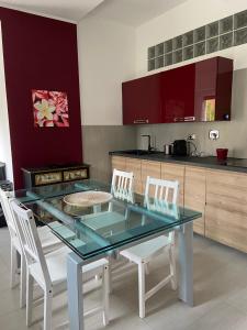 een keuken met een glazen tafel en witte stoelen bij Parrot's House tra mare e città in Acilia