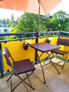 Duas cadeiras e uma mesa numa varanda com um guarda-sol em Helles Apartment mit Balkon am Großen Garten nahe Stadtzentrum em Dresden