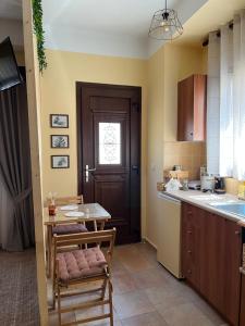 eine Küche mit einem Tisch, Stühlen und einer Tür in der Unterkunft GK Apartment in Chios