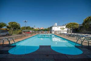 a swimming pool with blue water and tables and chairs at Camping Baltar in Portonovo