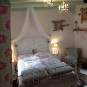 ein Schlafzimmer mit einem Himmelbett und einem Stuhl in der Unterkunft Ferienhaus mit Minibauernhof in Munster im Heidekreis