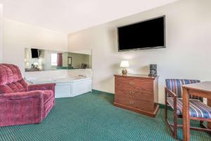 a hotel room with a tub and a chair and a television at Super 8 by Wyndham Platte City Kansas City Area in Platte City