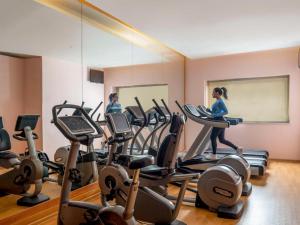 a woman running on cardio equipment in a gym at Novotel Bucharest City Centre in Bucharest