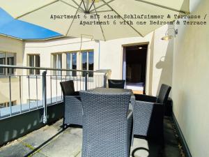 einen Tisch und Stühle auf einem Balkon mit Sonnenschirm in der Unterkunft Amaroo - Apartments Potsdam “Brandenburger Tor” in Potsdam