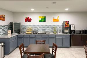 Quality Inn & Suites في كولومبوس: مطبخ مع دواليب زرقاء وطاولة مع كراسي
