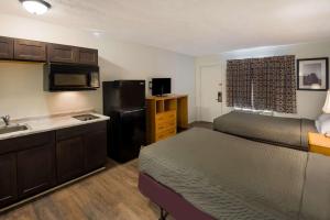 a small room with a bed and a kitchen with a sink at Suburban Studios Brazil in Brazil